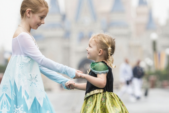 Little girl dressed as Elsa with sister dressed as Anna