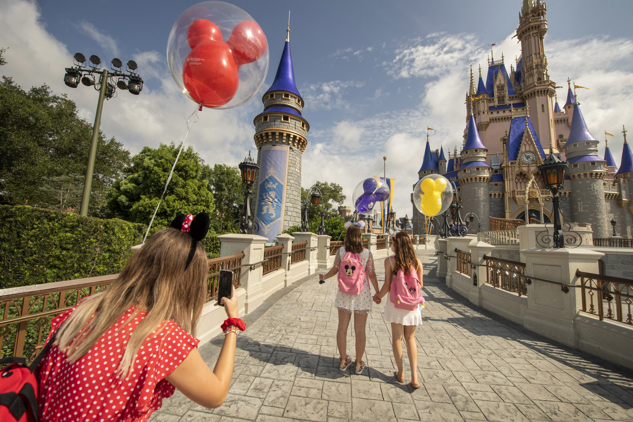 Teens walking away towards Cinderella Castle with balloons