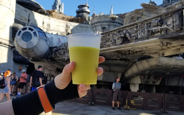 Green milk held up in front of Millennium Falcon