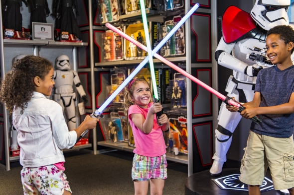 Kids playing with lightsabers in Launch Bay store