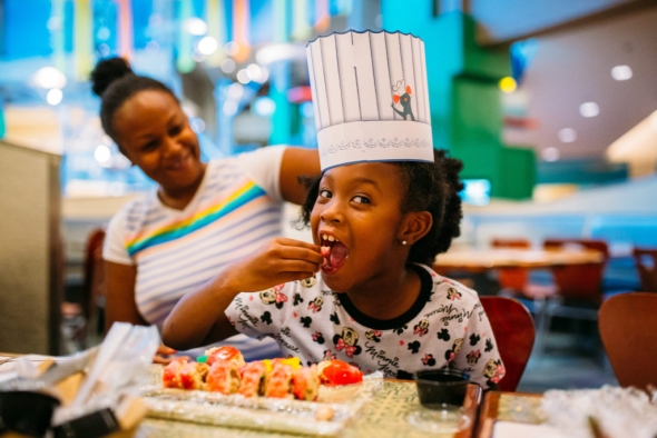 Little girl with chef hat eating candy sushi
