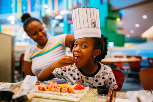 Adorable girl eating candy sushi with chef hat